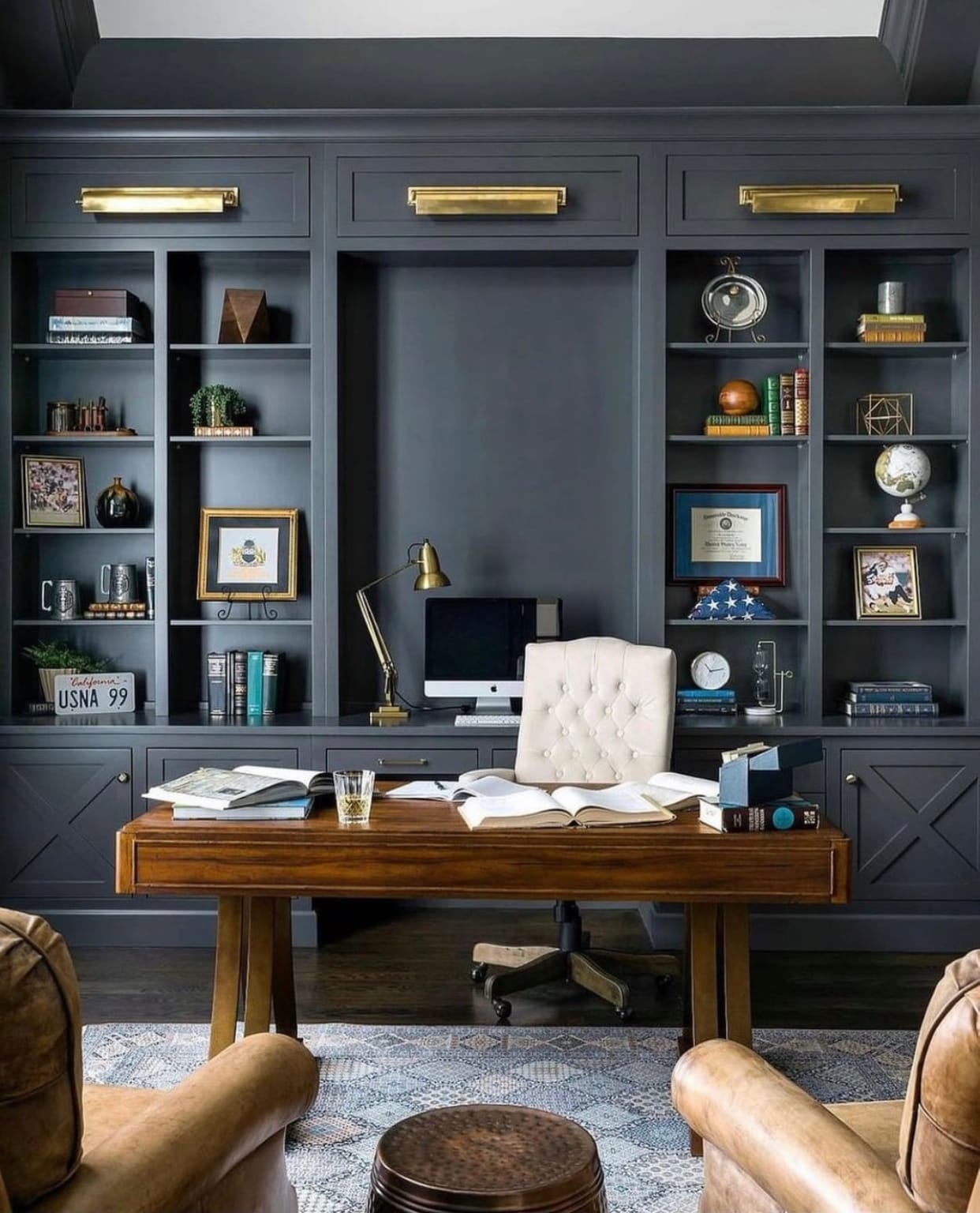 Elegant two-tone kitchen cabinetry with white upper cabinets, glass display doors, and deep blue lower cabinets with gold handles
