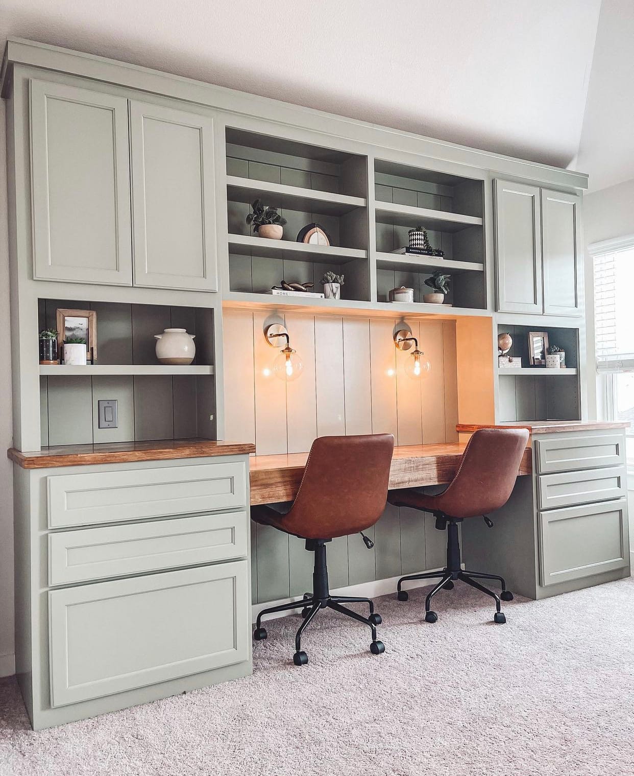 Elegant custom home office built-in with soft green cabinetry, natural wood countertop, and designer lighting for dual workspaces.