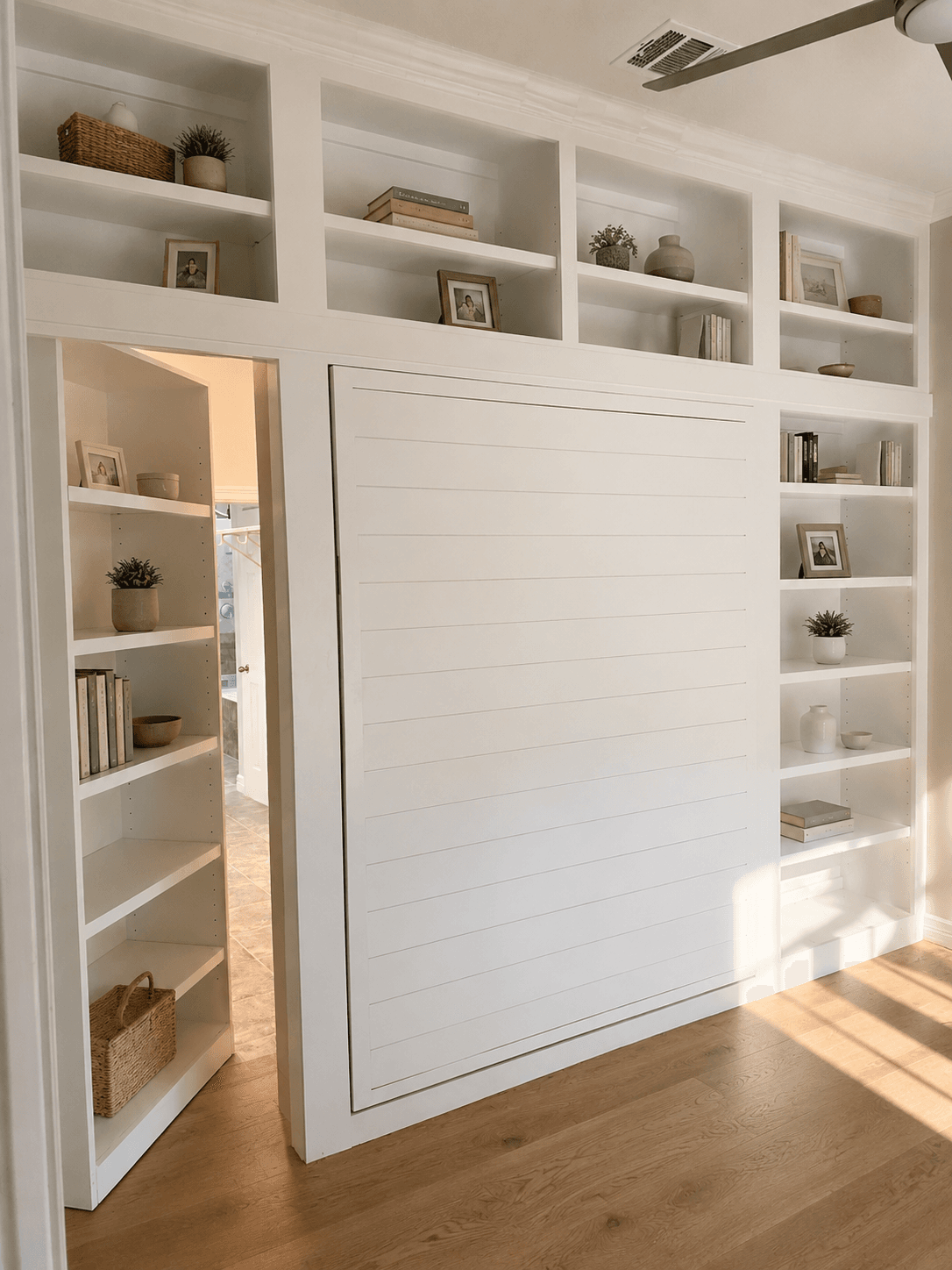 Custom Murphy bed wall with shelving and a concealed bookcase door